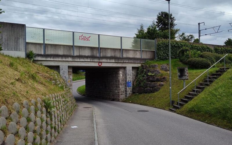 Unterführung Hännisweg: schmaler Weg unter der Bahnlinie, links eine Stützmauer.
